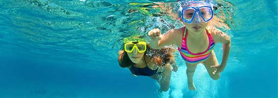 Mother with child swim underwater with fun in sea