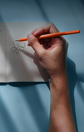 Hands doodling in a notebook.