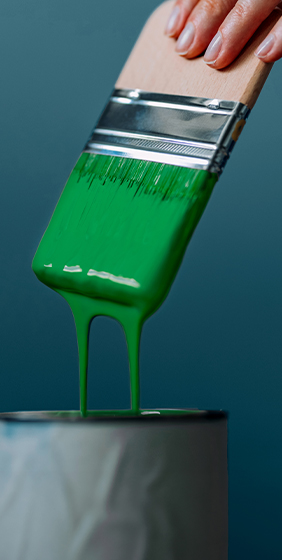 Paintbrush covered in dripping green paint.