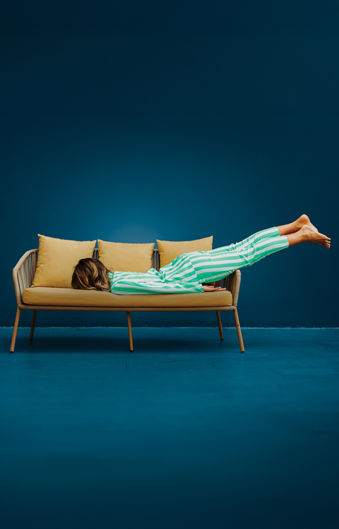 Woman in her pajamas, lying face-down in a small couch.
