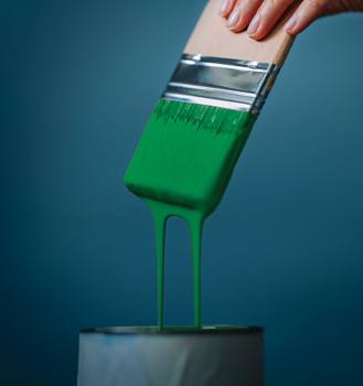 Paintbrush covered in dripping green paint.
