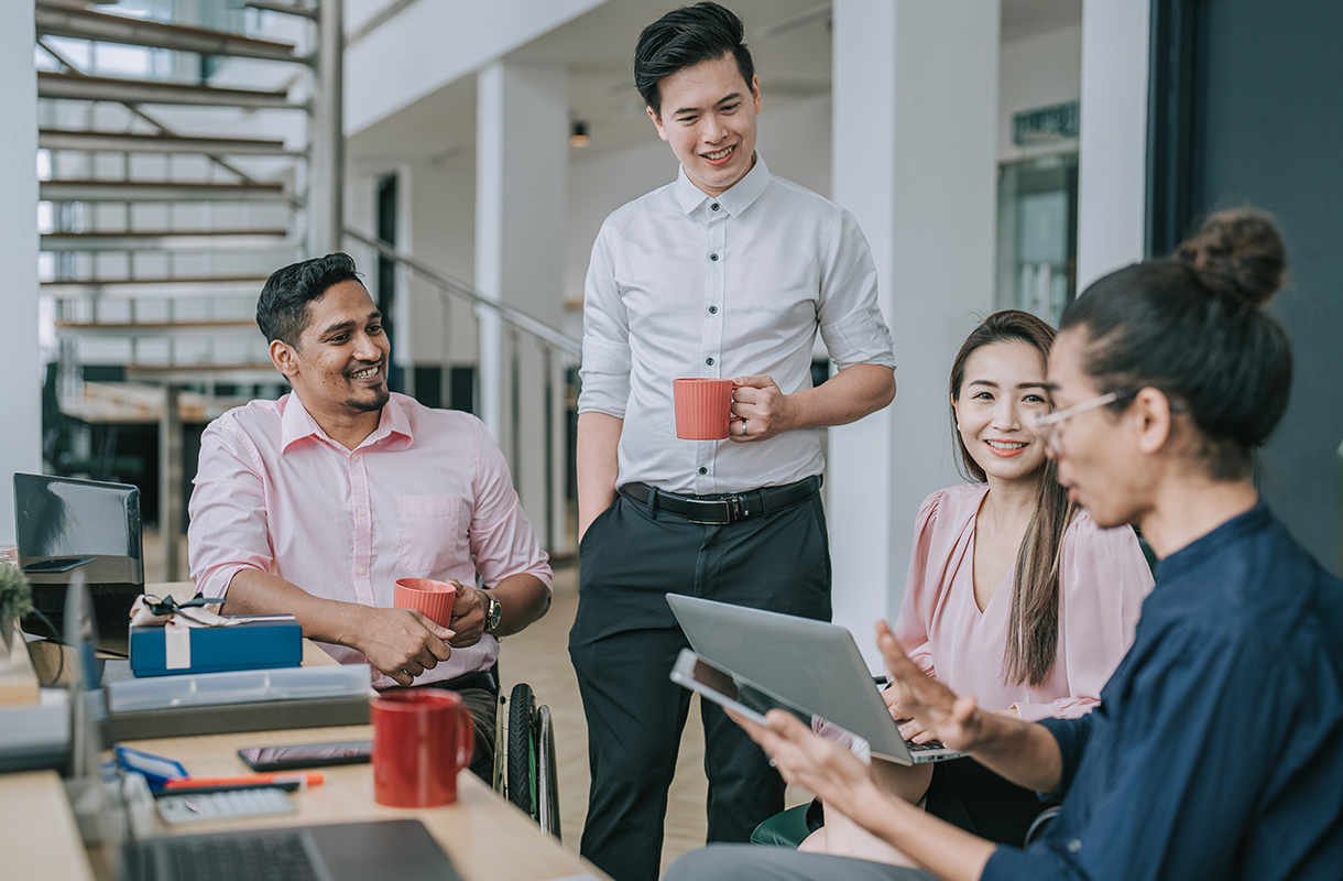Colleagues gathered around a desk in a modern office